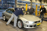 Op de remmentestbank terwijl Henny de voorruit inspecteert. Nic staat op de achtergrond toe te kijken.